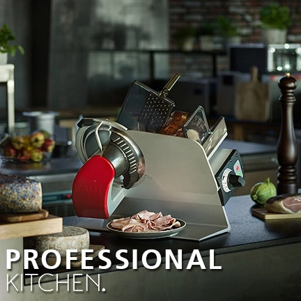 Professionelle Küche mit Fleischschneidemaschine und Essen auf dem Tisch.